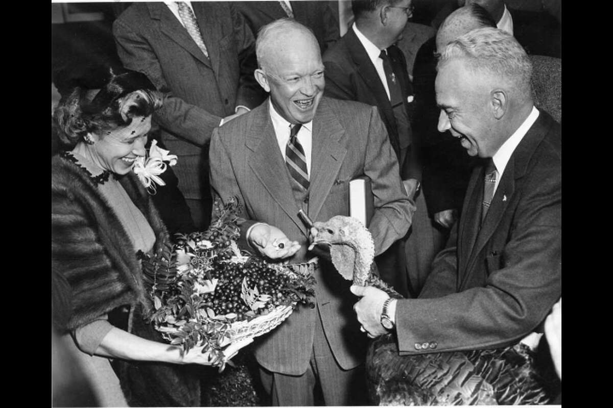 Dwight D. Eisenhower receives a 43-pound turkey from Perry Browning of Winchester, Kentucky, president of the National Turkey Federation. Eisenhower holds the book, “Turkey Management,” which was also presented. The presentation took place outside at the White House, Nov. 14, 1954.