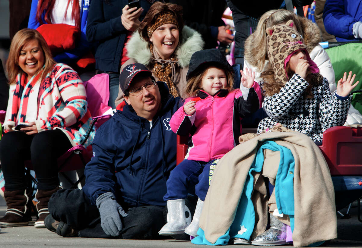 Orlando Turner, left, watches as his granddaughters Addisynn Turner, 3, center, and Becca Lanier, right, waves to participants during the 64th annual Thanksgiving Day Parade along Milam Street, Thursday, Nov. 28, 2013, in Houston.