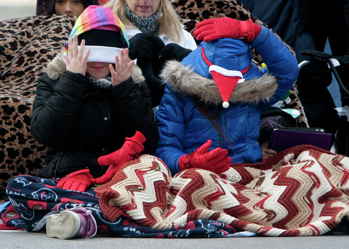 Kailee Frost, 11, left, and her cousin Rylee Frost, right, 9, adjust their warm weather gear as they wait for the start of the 64th annual Thanksgiving Day Parade along Walker Street Thursday, Nov. 28, 2013, in Houston.