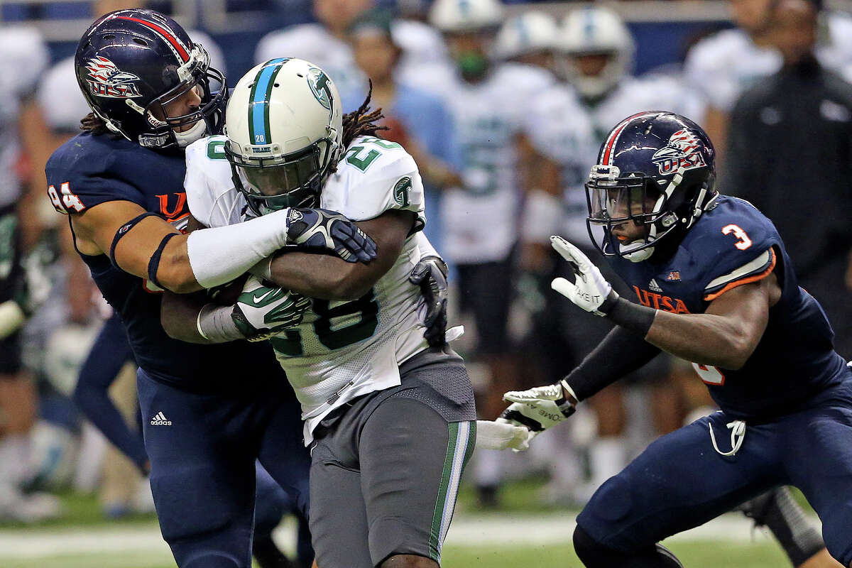 Tulane running back Rob Kelley chugs along with Roadrunner defenders Codie Brooks (94) and Cody Berry trying to stop him as UTSA hosts Tulane at the Alamodome on November 10, 2013.