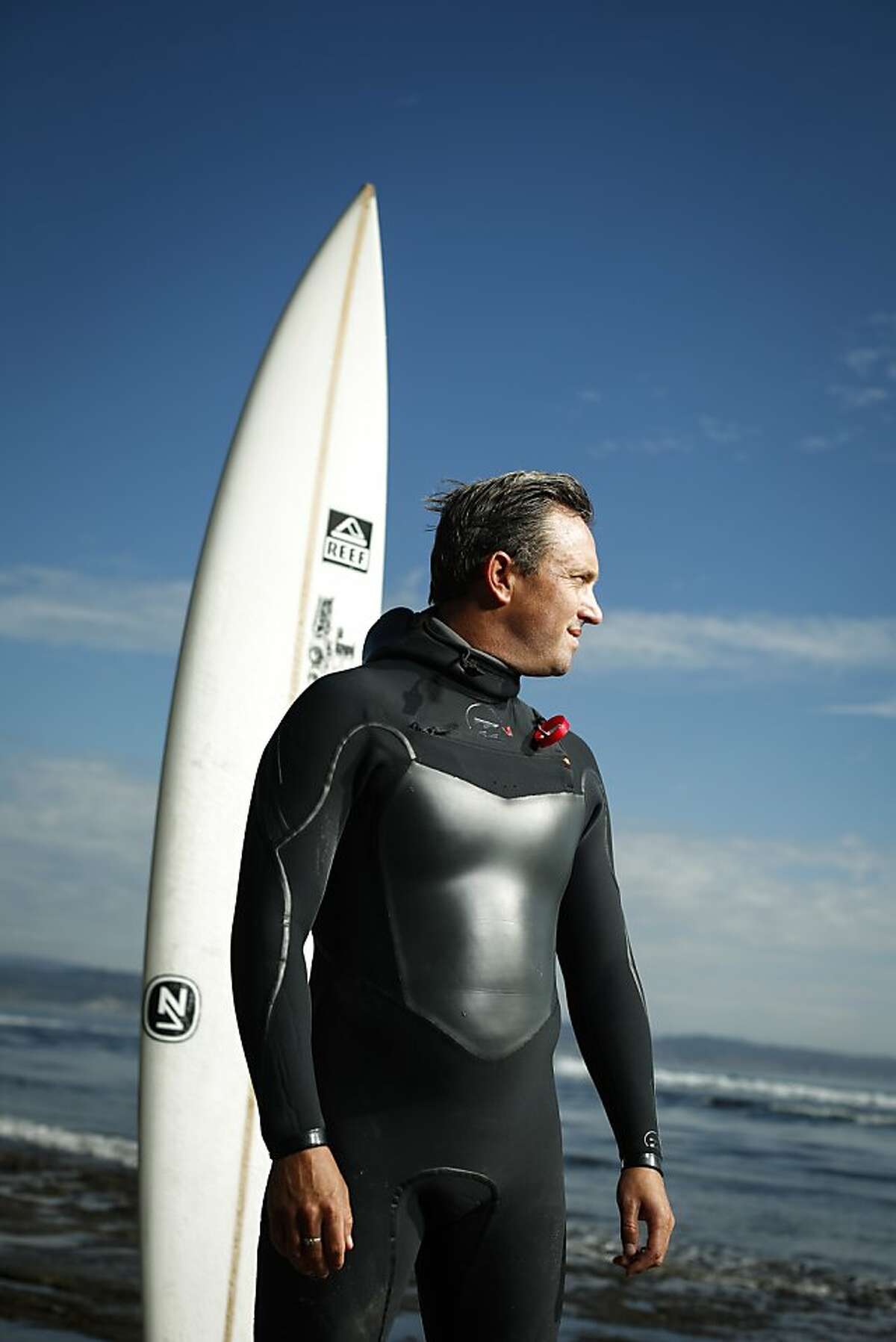 Shawn Dollar is seen at a beach in Santa Cruz, Calif., on Tuesday, Nov. 12, 2013 with the board he rode catching a record 61-foot wave at the Cortes Bank.