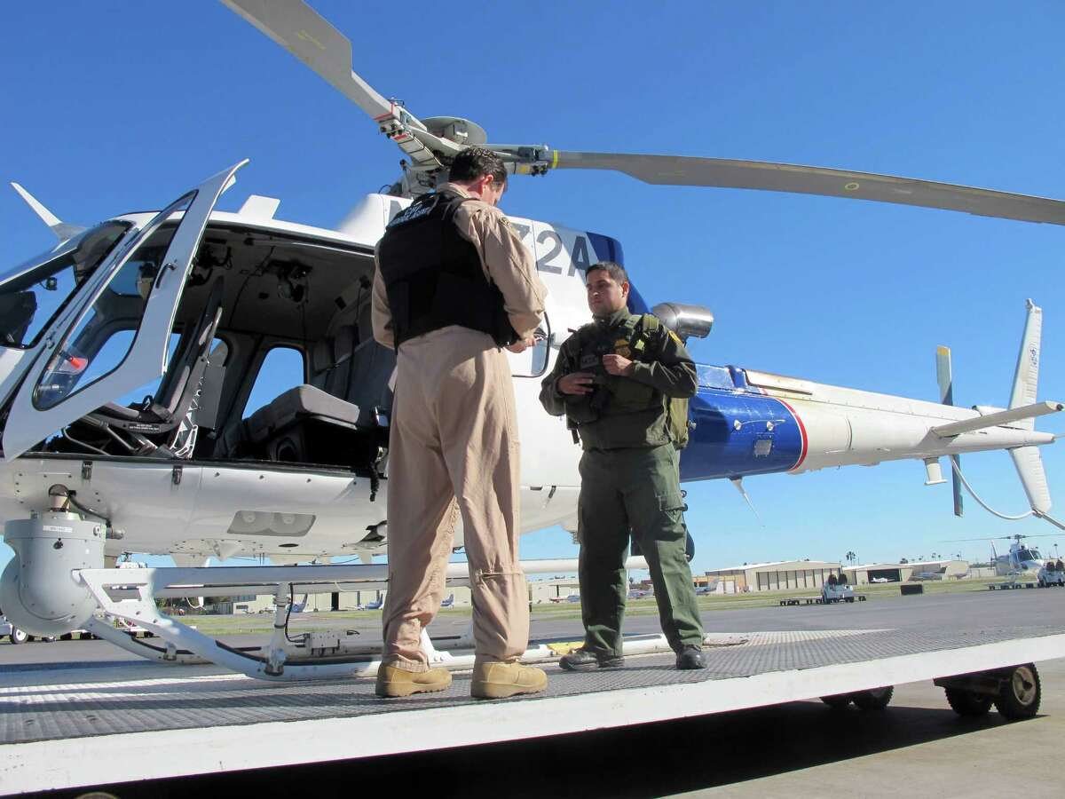 In this Nov. 27, 2013 photo U.S. Customs and Immigration Enforcement Office of Air and Marine Supervisory Air Interdiction Agent Jacob Dreher, left, and Border Patrol agent and emergency medical technician Mentor Cavazos demonstrate preparations on at the agency's Office of Air and Marine in McAllen, Texas. The Border Patrol began sending EMTs on regular helicopter patrols in the region to more quickly provide aid to immigrants and agents in distress. (AP Photo/Christopher Sherman)