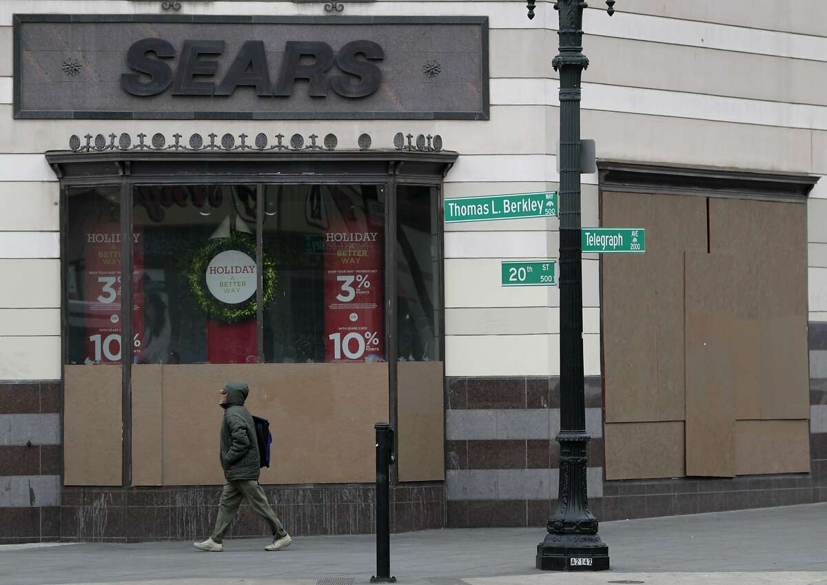 A man walks past a holiday window display partially obscured with plywood at the Sears department store on Telegraph Avenue in Oakland, Calif. on Tuesday, Dec. 3, 2013. The display windows were heavily damaged during demonstrations after the George Zimmerman verdict in July and store management has been slow to replace them claiming it's too expensive.
