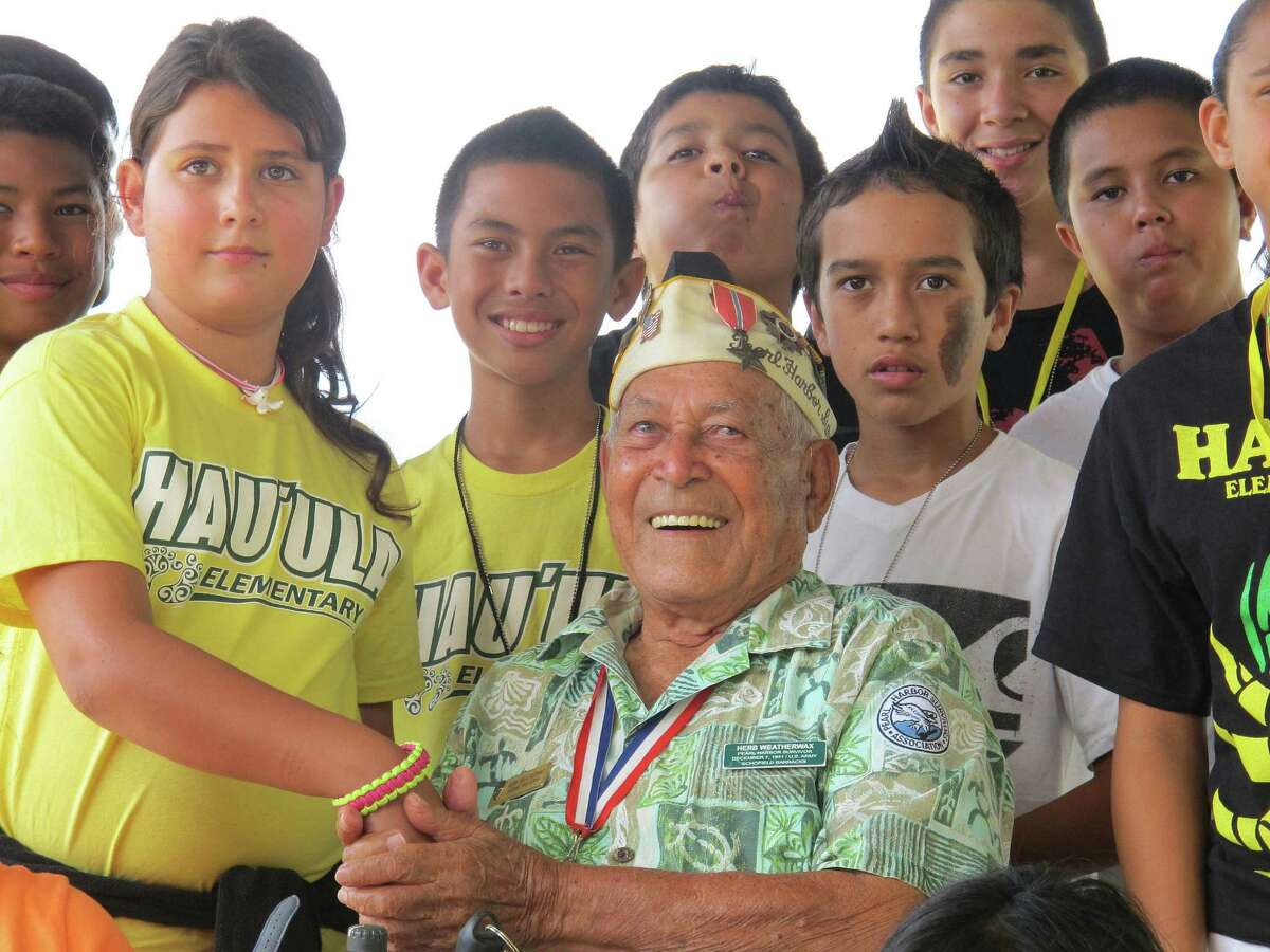 Pearl Harbor survivor Herb Weatherwax, 96, poses with Hauula Elementary School sixth-graders in Pearl Harbor, Hawaii. He volunteers at the historic site.