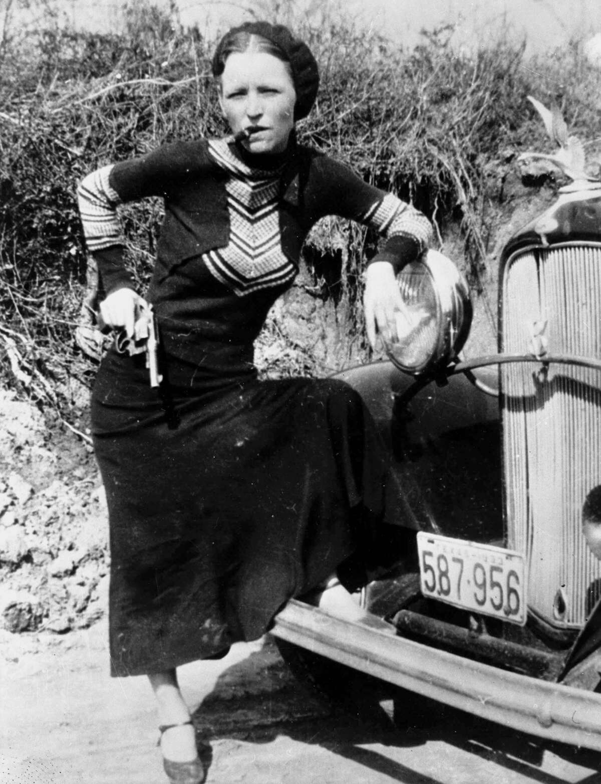 Bonnie Parker poses with a cigar and gun in a photo made infamous by the press, circa 1932.