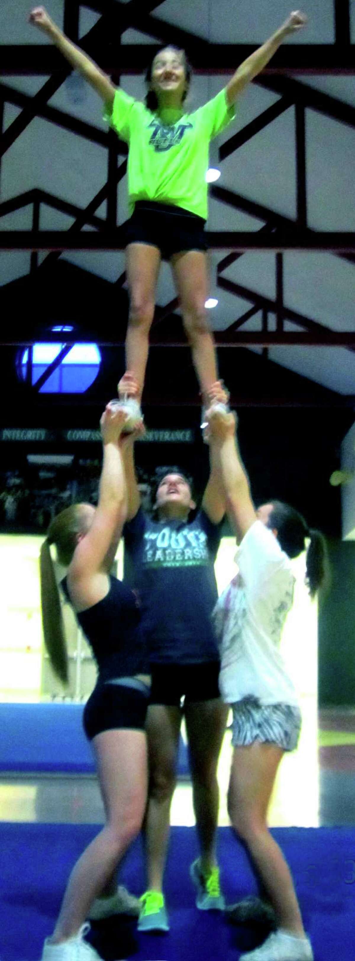 The Green Wave cheerleaders tune up for the 2013-14 winter season. Here, flyer Miranda Nuggett finds herself nearly in the rafters of the New Millford High cafeteria thanks to a boost from teammates, from left to right, Courtney Pecora, Sydney Fairchild and Meghan Timan. Dec. 9, 2013
