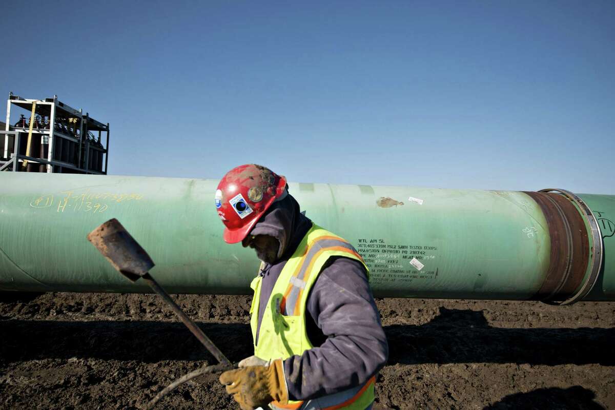 A worker carries a torch after heating a pipe joint during pipeline construction in Atoka, Okla., in March. TransCanada said it “began to inject oil into the Gulf Coast Project pipeline as it moves closer to the start of commercial service.”