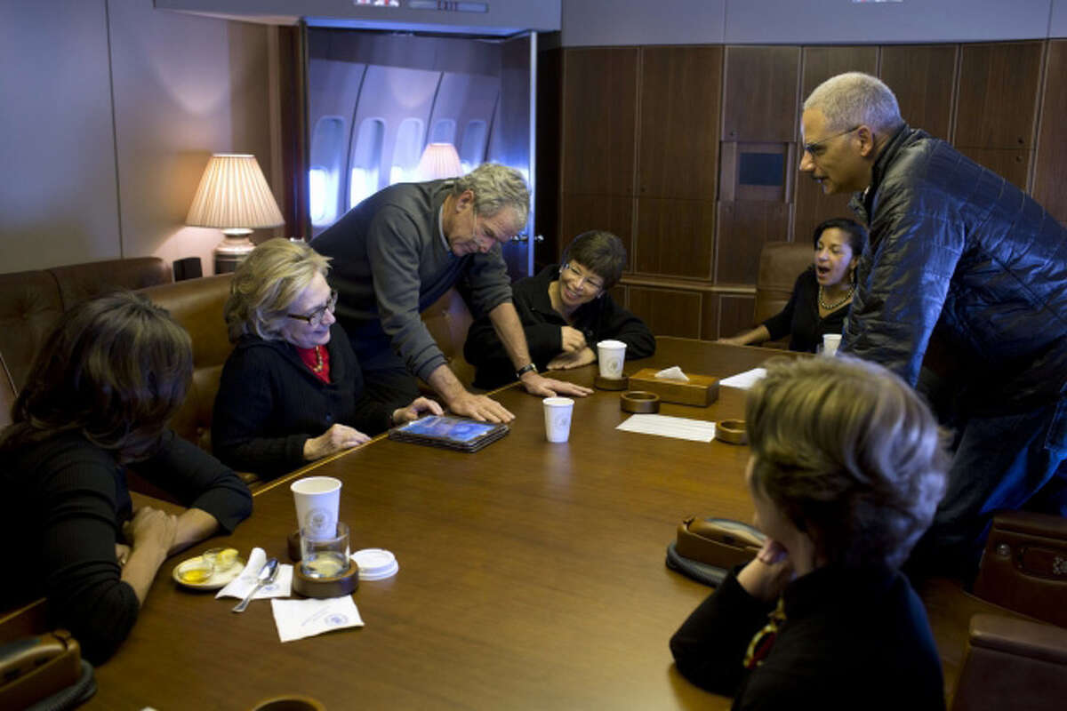 Aboard Air Force One, former President Bush shows photos of his paintings to, from left, First Lady Michelle Obama, former Secretary of State Hillary Clinton, Valerie Jarrett, National Security Advisor Susan E. Rice, Attorney General Eric Holder and former First Lady Laura Bush, Dec. 9, 2013. (Official White House Photo by Pete Souza)