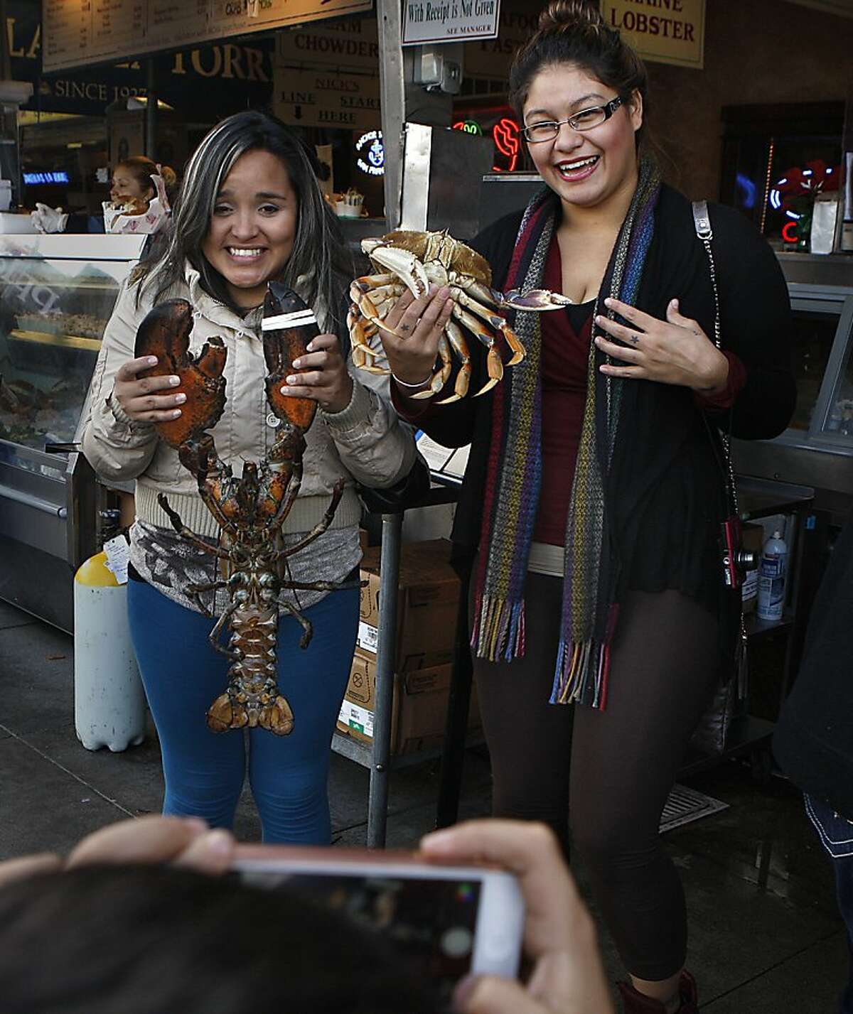 Sisters from out of town pose with a live lobster and crab at Nick's Lighthouse, a wharf restaurant destination since 1934, in San Francisco, Calif., for their nephew/son on Monday, December 2, 2013.