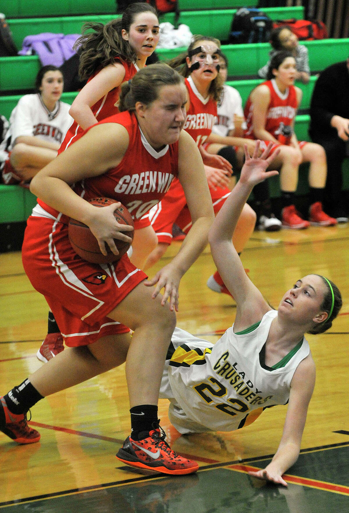 Greenwich's Emily Anderson dribbles around the diving Anne Peltier, of Trinity Catholic, during their game at Trinity Catholic High School in Stamford, Conn., on Wednesday, Dec. 11, 2013. Greenwich won, 68-32.