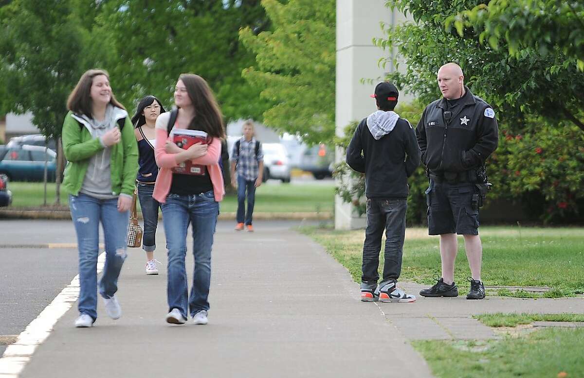 Albany police school resource officer Curtis Bell talks with a student while greeting teenagers as they arrive at West Albany High School, Tuesday, May 28, 2013. One of their classmates, a 17-year-old junior, was arrested late last week and charged with plotting to blow up the school. (AP Photo/Albany Democrat-Herald, Mark Ylen)