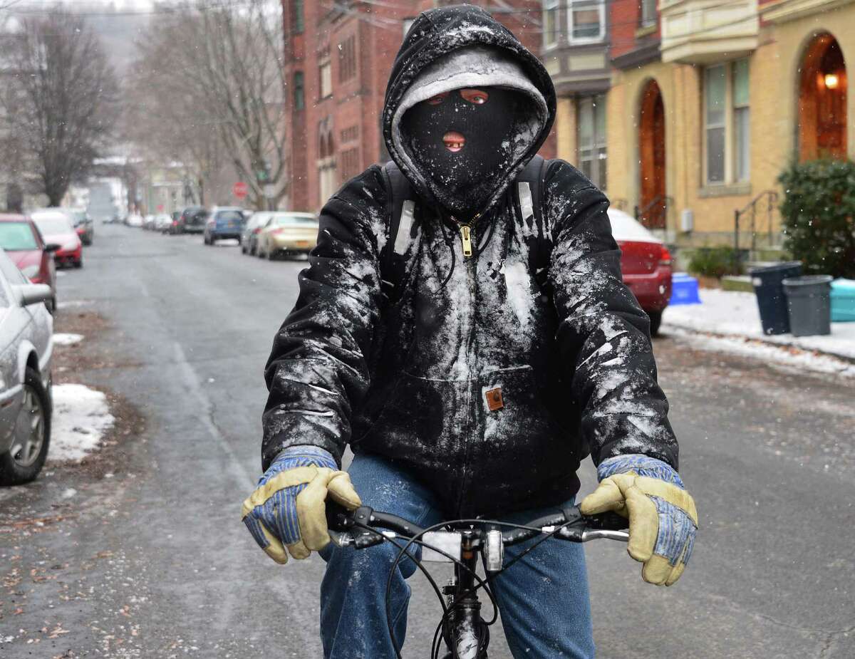 Joe Kehn of Troy rides his bicycle through a snow squall along Washington Street while riding to the market Friday, Dec. 13, 2013, in Troy, N.Y. (John Carl D'Annibale / Times Union)