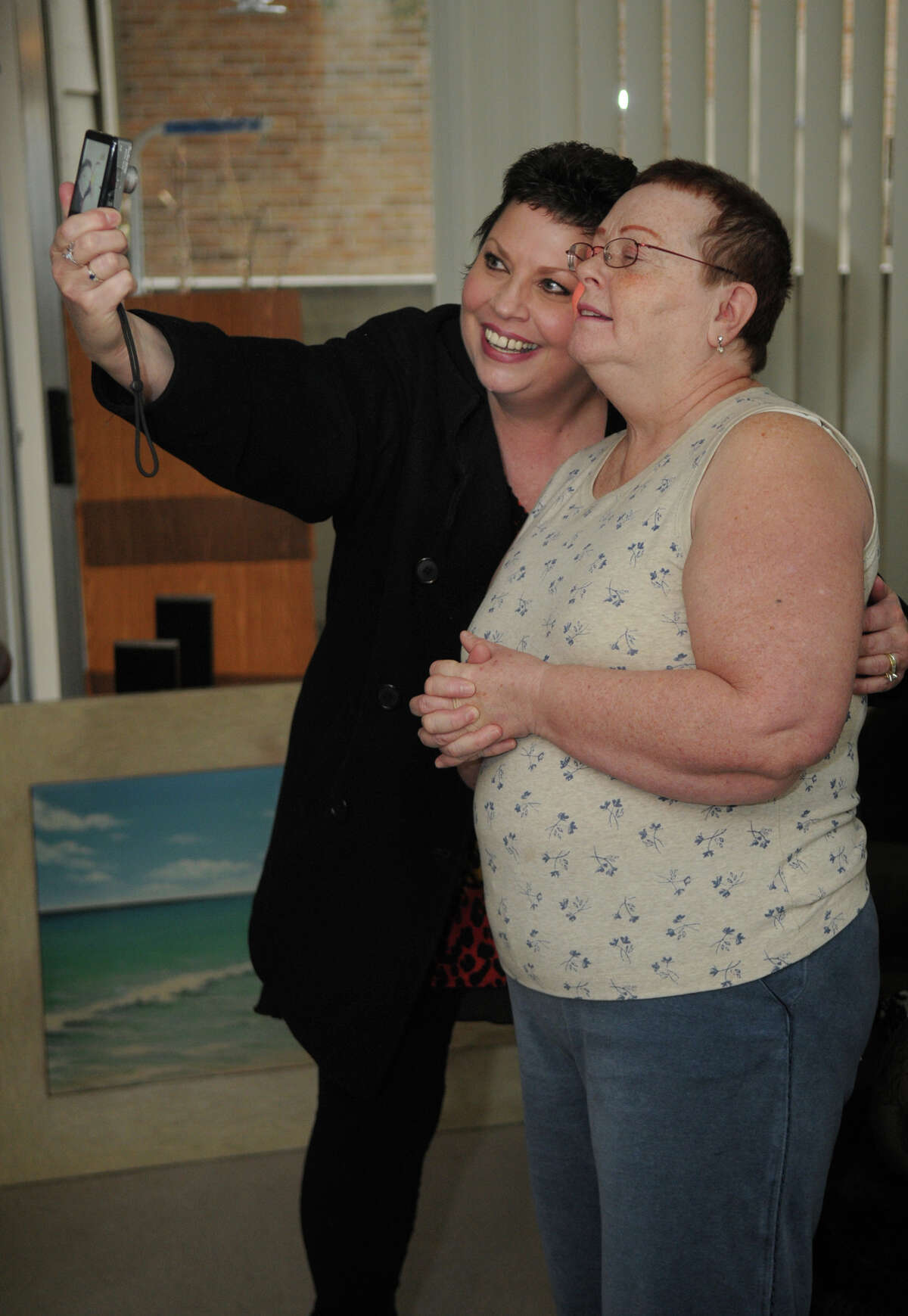 Kelly Quin, from left, takes a selfie with friend Karen Klaus, of The Woodlands, who was surprised with a houseful of furniture by Georgia Ann Spears of Gallery Furniture during their annual Christmas Giveaway on Friday.