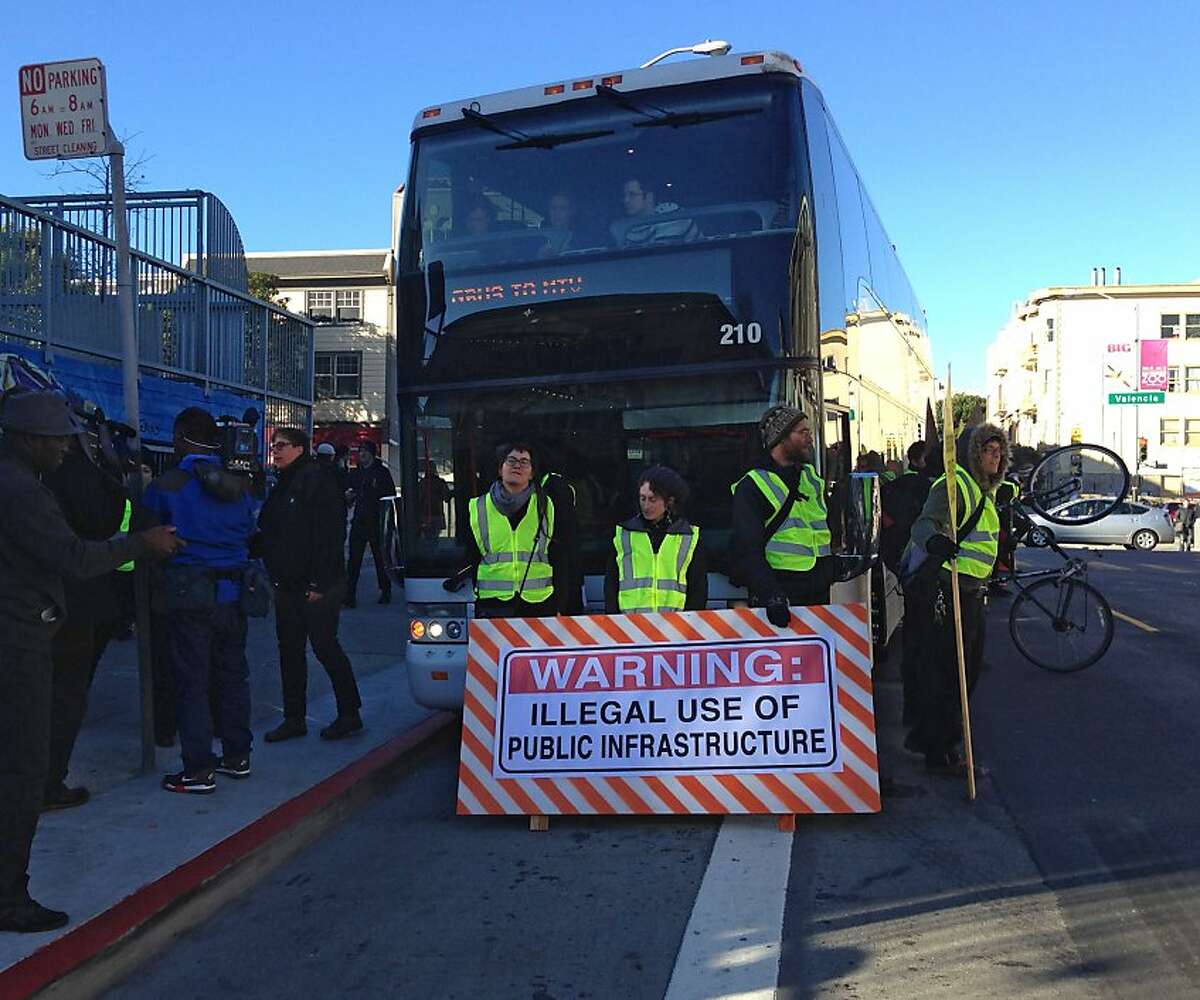 Protesters surround and block a Mountain View-bound Google employee commuter bus Monday morning at a Muni bus stop at 24th and Valencia streets in San Franciscoâ€™s Mission District. The demonstration delayed the bus and its riders for about half an hour while protesters held up signs and chanted against private buses using Muni buses to pick up employees.