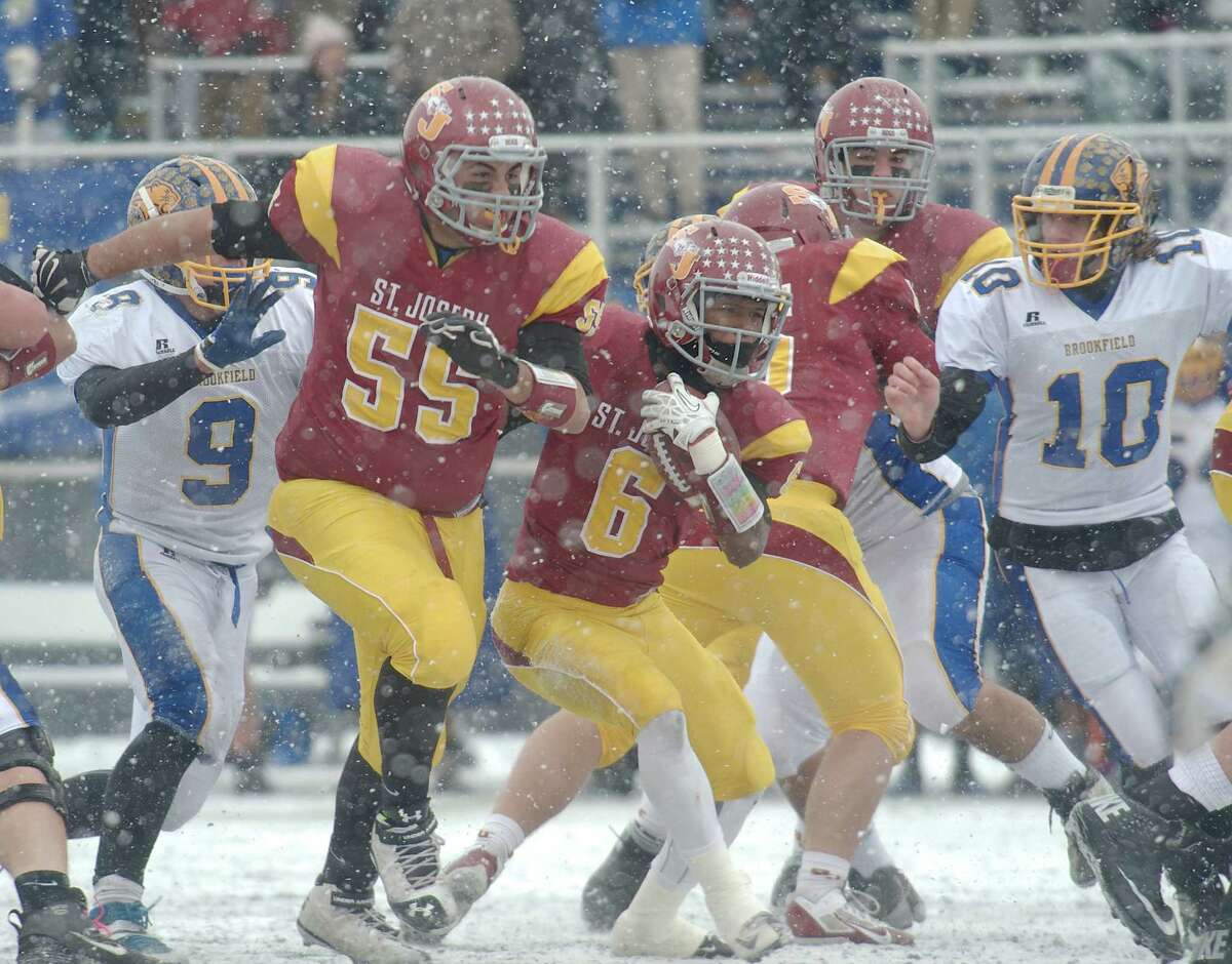 St Joseph's Mufasha Abdul Basir (6) cuts past lineman Troy Vazzano (55) during the Class M football championship game between Brookfield and St Joseph high schools at Central Connecticut State University's Arute Field in New Britain, Conn, on Saturday, December 14, 2013. Brookfield's Peter Manesis (10) moves in.