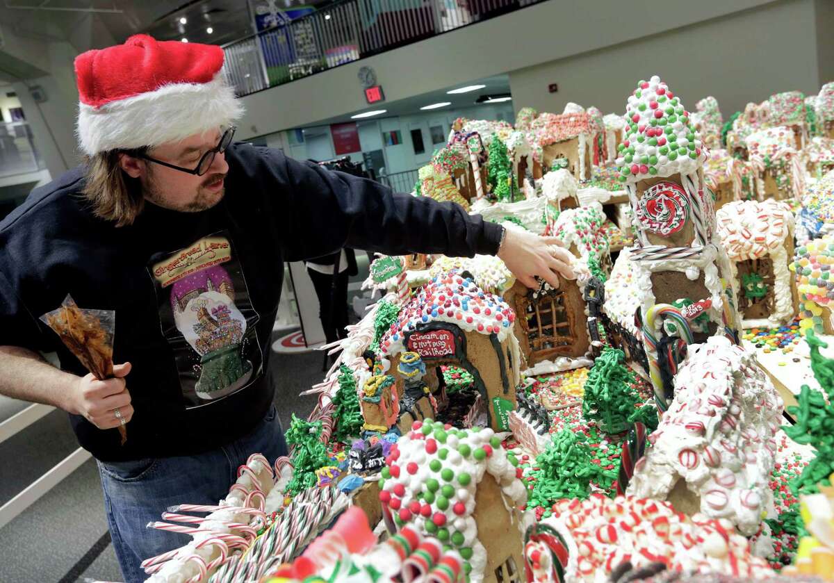 Chef and GingerBread Lane creator Jon Lovitch repairs one of the gingerbread houses of his annual showpiece, in the New York Hall of Science, in the Queens borough of New York, Thursday, Dec. 12, 2013. The 1.5-ton, 300-square-foot village that is made entirely of edible gingerbread, royal icing, and candy, has been acknowledged as the largest gingerbread village in the world by the 2014 Guinness World Records. (AP Photo/Richard Drew) ORG XMIT: NYRD116