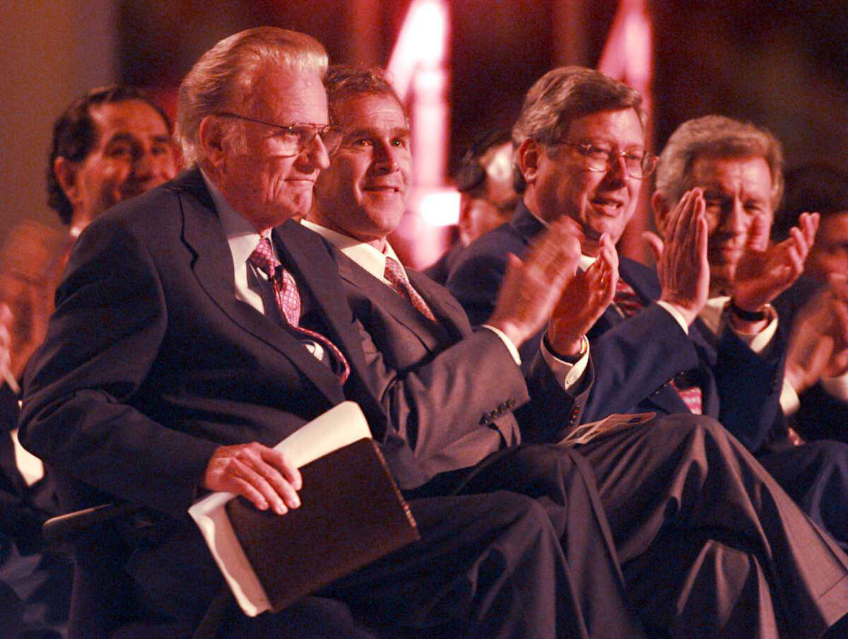 Billy Graham receives applause as he leaves his chair with his Bible to go speak on the first day of the crusade at the Alamodome, Thursday, April 3, 1997. On his right are Texas Gov. George W. Bush and San Antonio Mayor Bill Thornton.