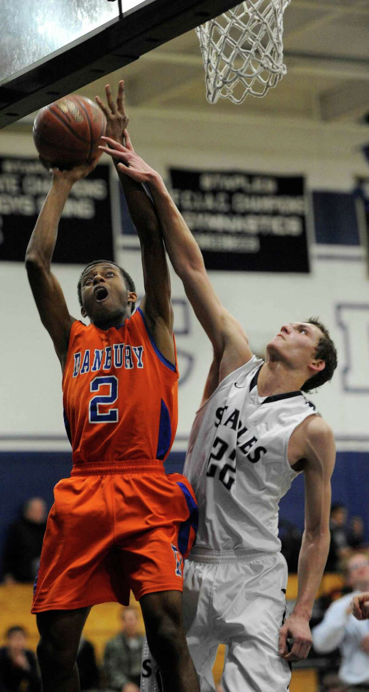 Staples high school's Nick Esposito tries to stop Danbury high school's Elijah Duffy from scoring a layup during a boys basketball game played at Staples, Westport, CT on Wednesday, December,18th, 2013.