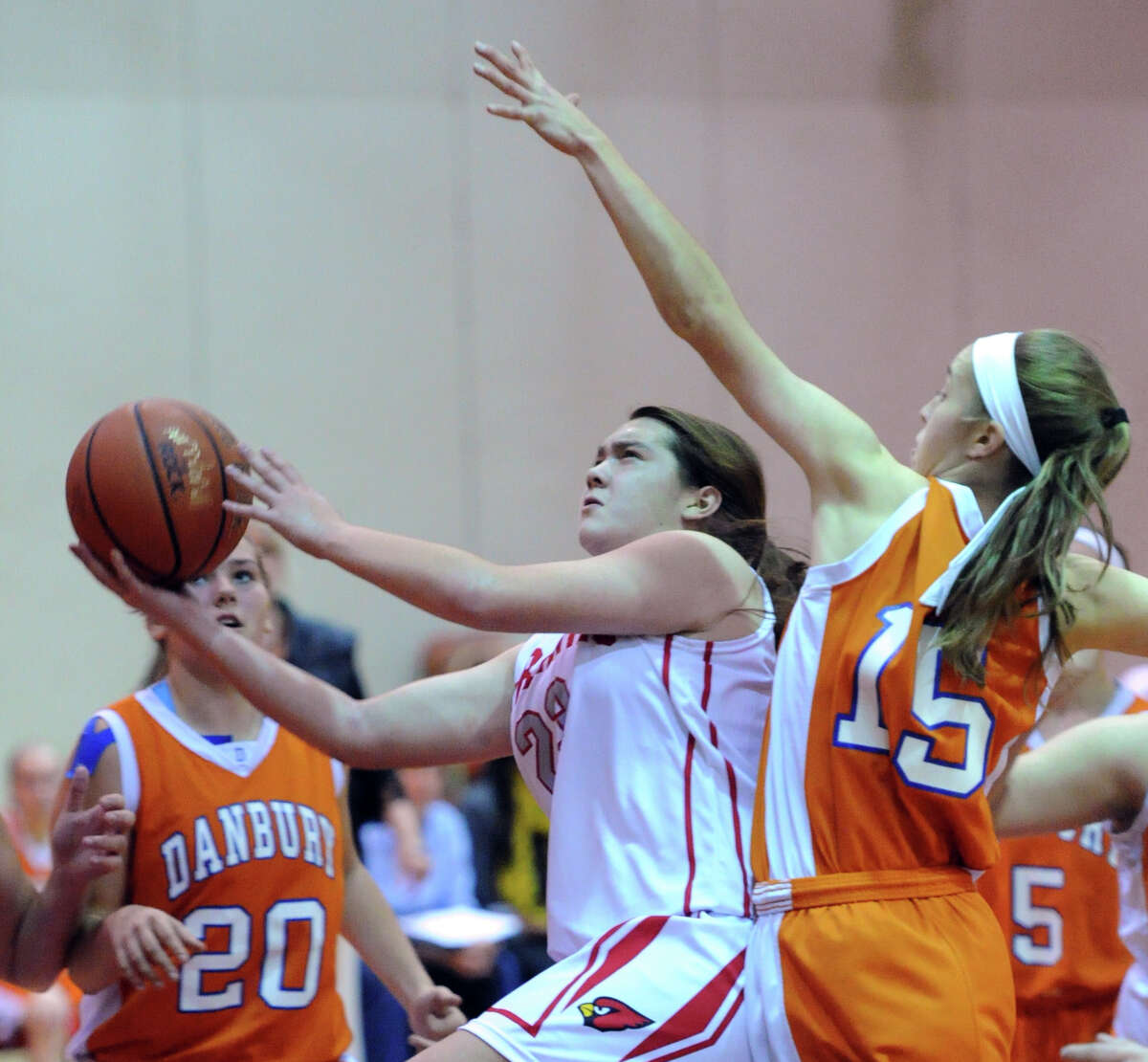 At center, Jamie Kockenmeister (# 23) of Greenwich goes in for a lay-ip while being defended by Danbury's Rebecca Gartner (# 15), right, during the girls high school basketball game between Greenwich High School and Danbury High School at Greenwich, Friday night, Dec. 20, 2013. At left is Allie Smith (# 20) of Danbury.