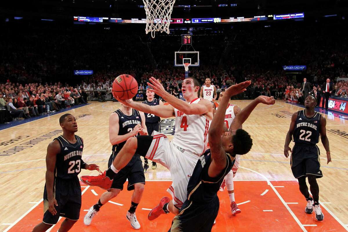 Ohio State's Aaron Craft (4) draws a foul while scoring against Notre Dame's Eric Atkins during the first half of an NCAA college basketball game Saturday, Dec. 21, 2013, in New York. (AP Photo/Jason DeCrow) ORG XMIT: NYJD103