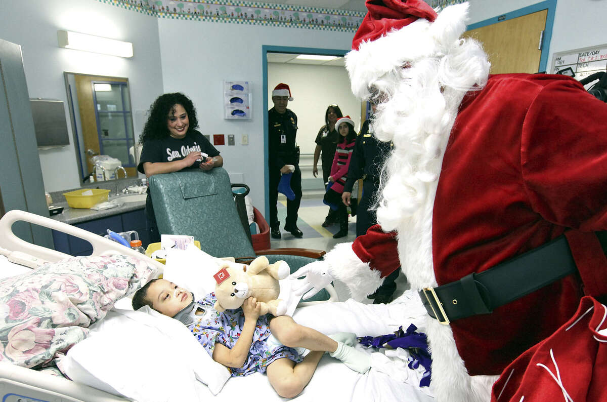 Six-year-old Andres Garcia gets a teddy bear from Santa as the young patient’s mom, Esmeralda Garcia, watches her son’s reaction.