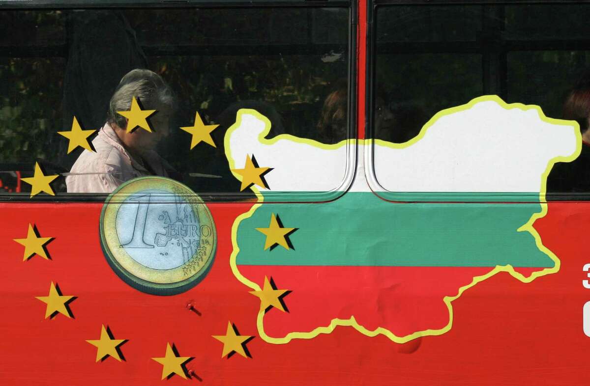 FILE - In this Sept. 25, 2006 file photo, a man reads a newspaper behind a bus window painted with the EU sign and a map of Bulgaria, in Sofia. For months, Britainâs tabloid newspapers have repeatedly warned of the horrors that will ensue on Jan. 1, 2014 when work restrictions will be lifted across the European Union for migrants from Romania and Bulgaria - two of the trading blocâs newest members. (AP Photo/Petar Petrov, File)