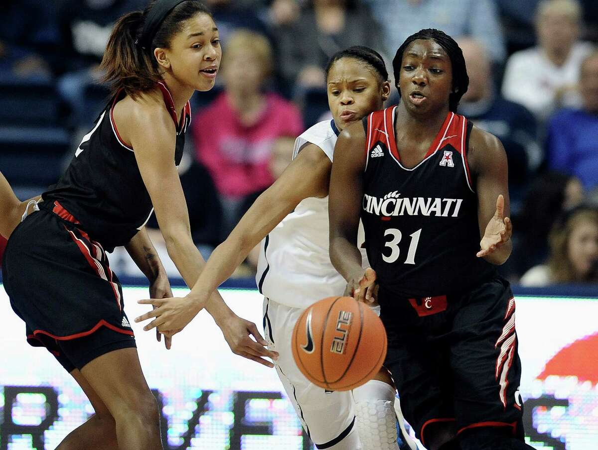 Connecticut's Moriah Jefferson, center, intercepts a pass-attempt from Cincinnati's Alyesha Lovett to Dayeesha Hollins, right, during the first half of an NCAA college basketball game on Sunday, Dec. 29, 2013, in Storrs, Conn.