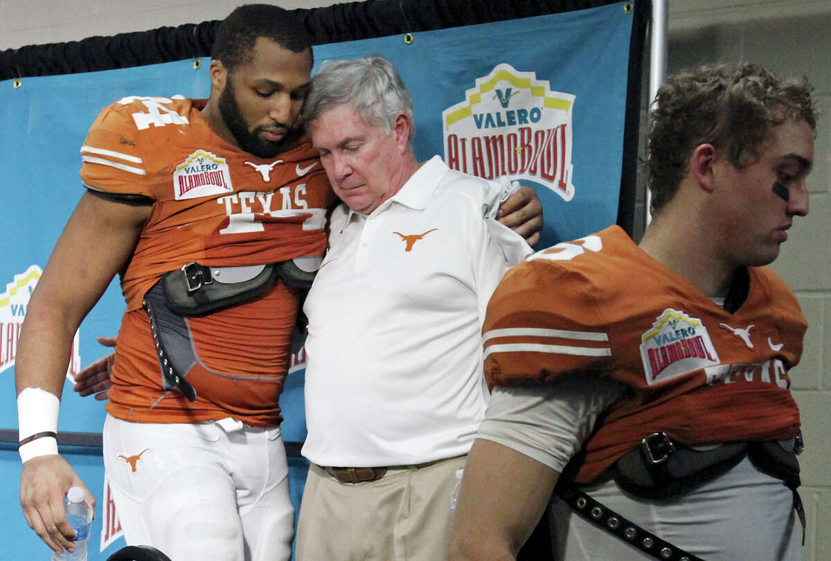 Texas Longhorns' Jackson Jeffcoat (from left) hugs head coach Mack Brown as Case McCoy walks off after a press conference for the Valero Alamo Bowl with the Oregon Ducks Monday Dec. 30, 2013 at the Alamodome. Oregon won 30-7.