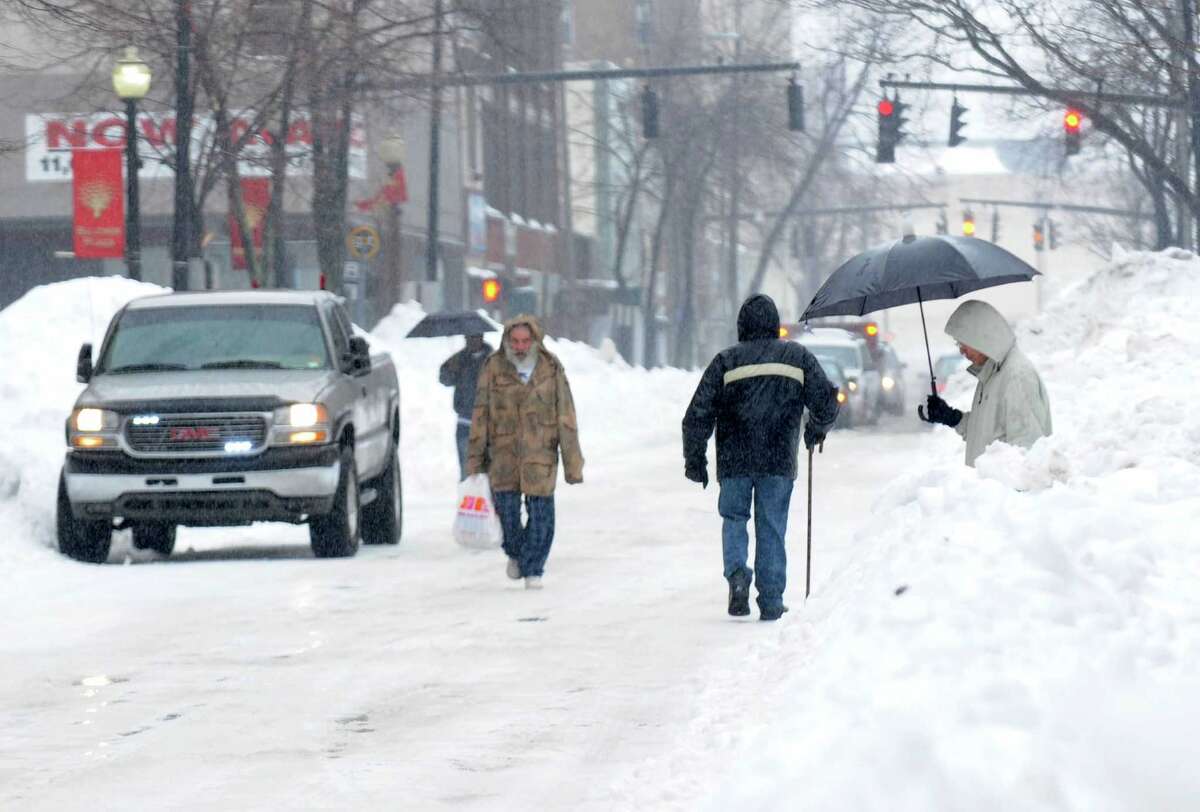 Pedestrians continue to struggle to get around the city as they walk around vehicles and snowbanks on Main St. in Bridgeport, Conn. on Monday Feb. 11, 2013.