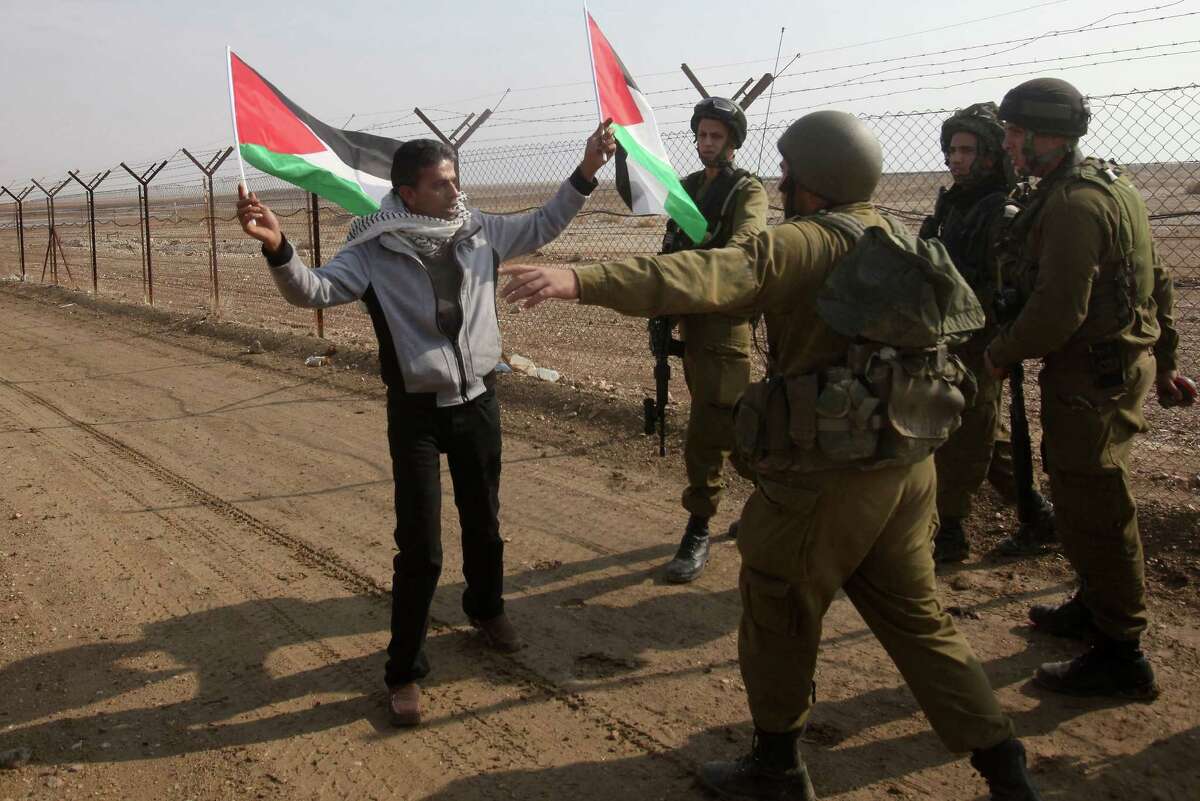 Israeli security forces prevent a Palestinian protester from affixing a Palestinian flag on the Jordanian-Israeli border fence during a rally Wednesday near Jericho.