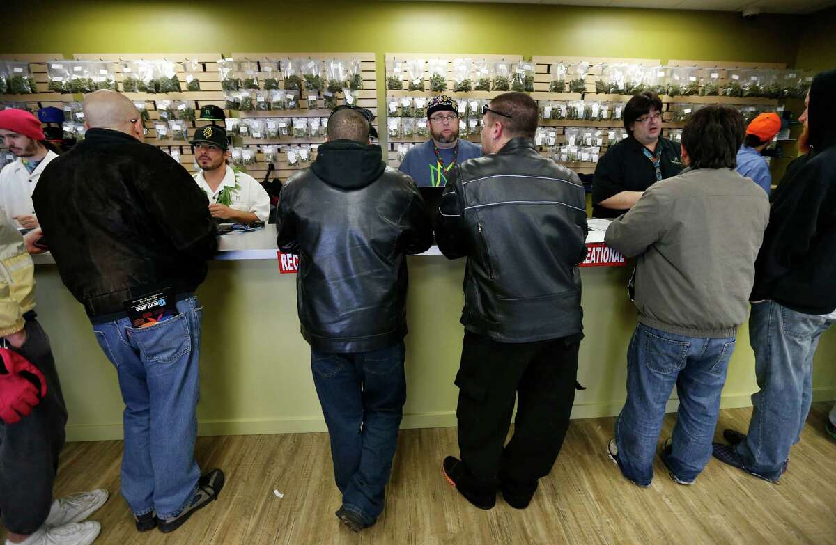 Employees help customers at the crowded sales counter inside Medicine Man marijuana retail store, which opened as a legal recreational retail outlet in Denver on Wednesday Jan. 1, 2014. Colorado began retail marijuana sales on Jan. 1, a day some are calling "Green Wednesday." (AP Photo/Brennan Linsley)