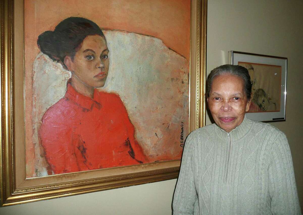 Nancy Brown stands in front of a portrait of her as a young girl, which was painted by the artist who would become her husband, David Brown.