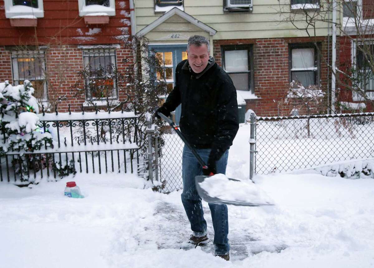 FILE- In this Jan. 3, 2014 file photo, New York City Mayor Bill de Blasio shovels the sidewalk in front of his house in New York. With less than 36 hours into his tenure, the first test of the new mayor?’s leadership skills arrived in the form of a major winter storm. (AP Photo/Seth Wenig, File) ORG XMIT: NYR401