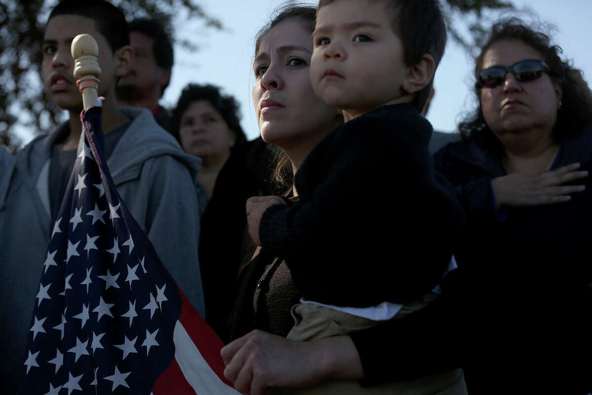Maria Posada holds her son, Dylan Dominguez, 16 months, as they watch the funeral procession for Officer Robert Deckard arriving at Mission Burial Park South in San Antonio on Saturday, January 4, 2014. Posada's husband and Dylan's father, SAPD officer Juan Dominguez, was in the procession.