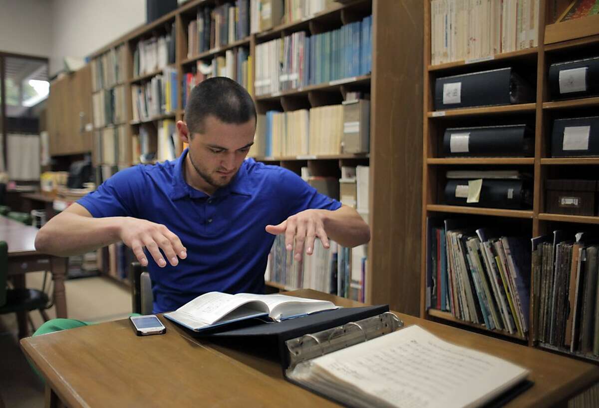 Joe Osborne, a student at Holy Names University, practices hand gestures for conducting music in the American Folk Music Collection archive at the university on Monday, November 11, 2013, in Oakland, Calif. Anne Laskey, and Gail Needleman have spent years working on an archive of American Folk music at Holy Names Univeristy and have begun an online version of their archive. A new grant would allow them to greatly expand the online archive's content.
