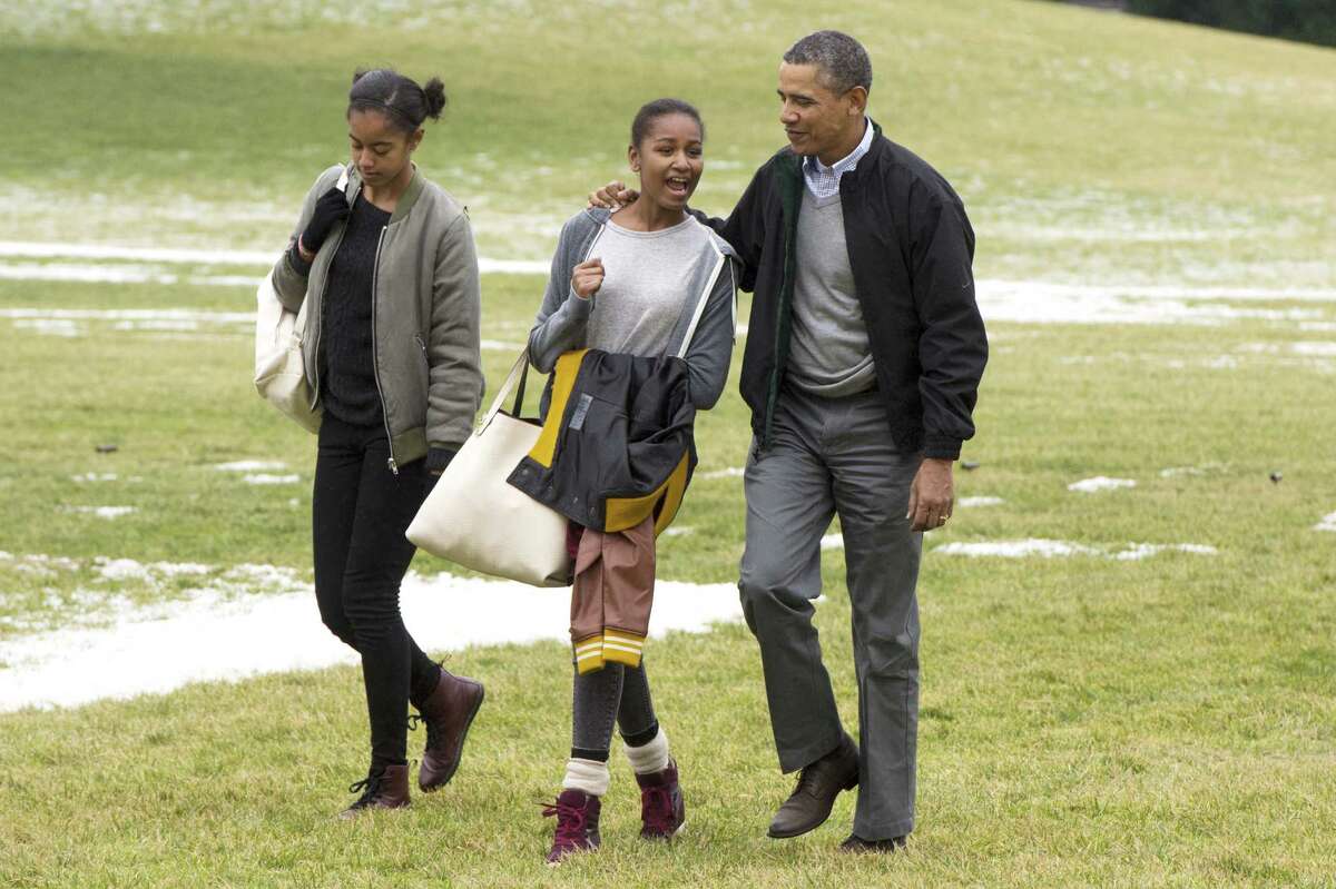 Malia and Sasha walk with their dad across the South Lawn at the White House after arriving by helicopter Marine One. The girls were returning from a two-week vacation in Hawaii. The whole family's color coordination is out of control.