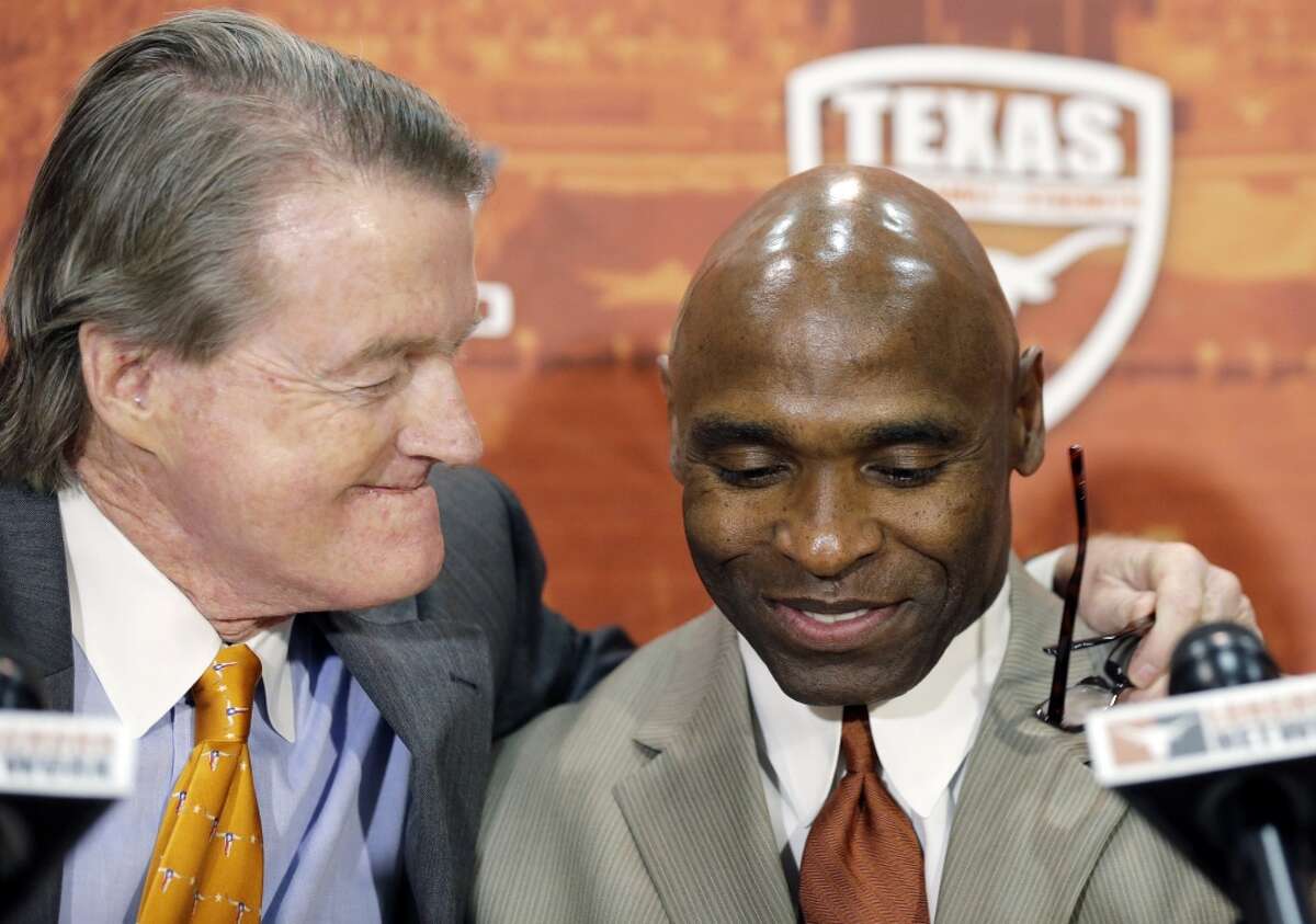 Charlie Strong, right, is hugged by Texas president Bill Powers, left, during the news conference.