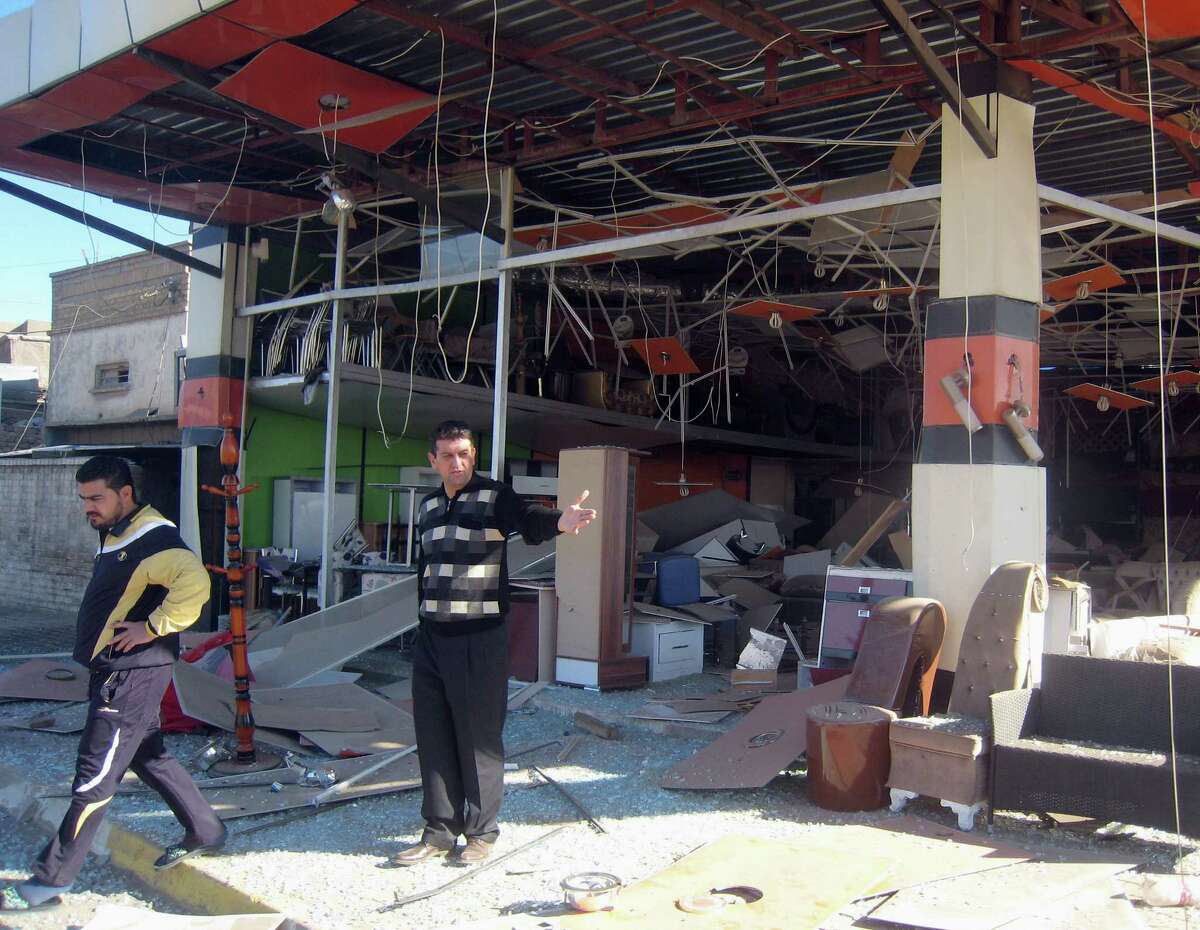 Civilians inspect the site of a suicide car bomb attack in Kirkuk, 180 miles (290 kilometers) north of Baghdad, Iraq, Tuesday, Jan. 7, 2014. Police said a suicide bomber rammed his explosives-laden truck into a police station in the northern city, home to a mix of Arabs, Kurds and Turkomen, each of the ethnic groups has competing claims to the oil-rich area. (AP Photo/Emad Matti)