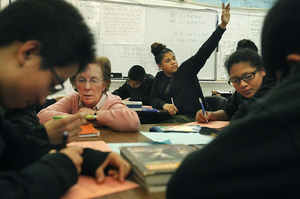 Tiara Vandigriff, 13, center, raises her hand for help while students work around her, from left, Simon Wong, 13, Johnny Yu, 14, (not visible) gets help from Instructional Reform Facilitator Ann Lyon, with Helen Villanueva, 13, at right, during an 8th grade Algebra class December 19, 2013 at James Denman Middle School.