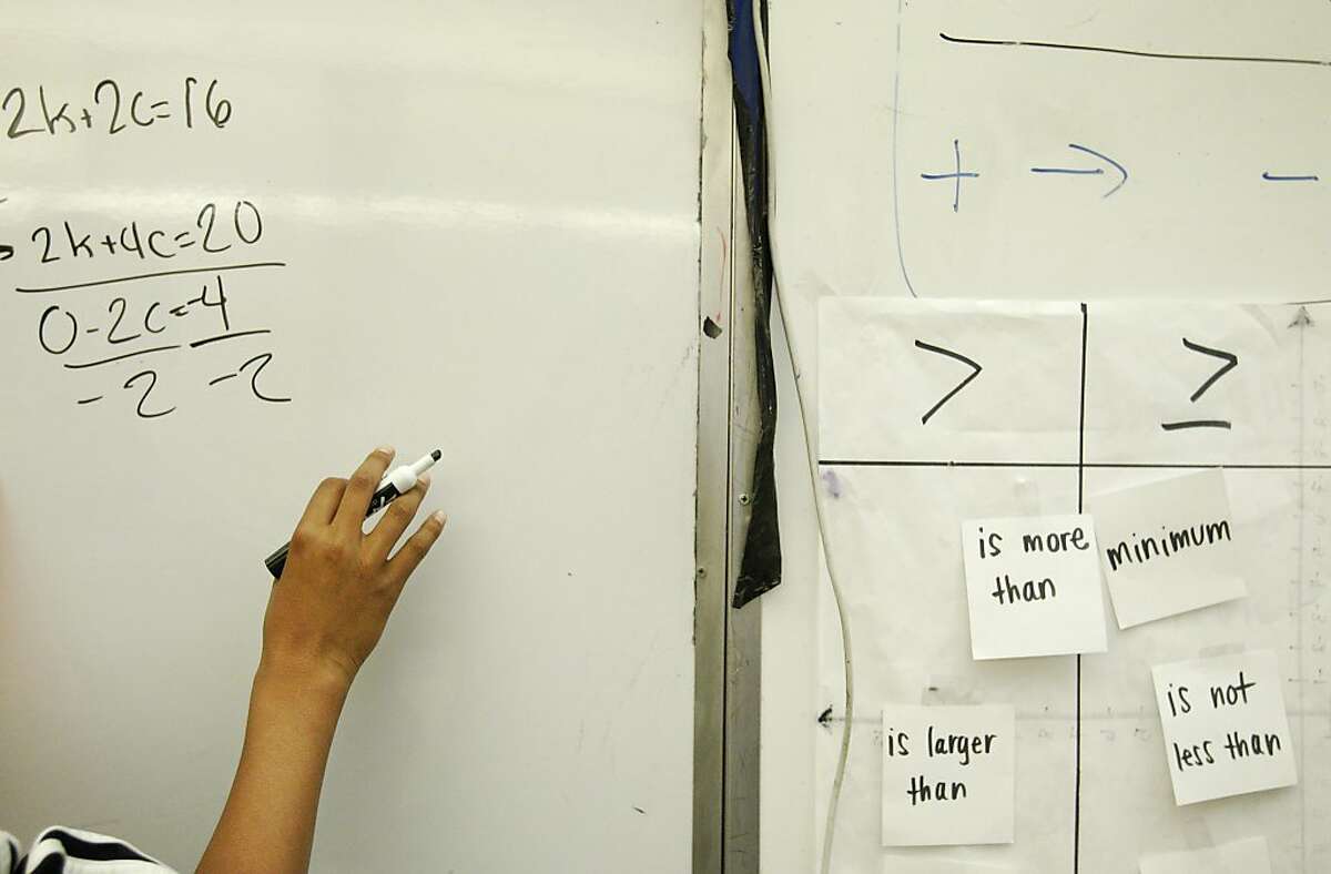 Antonio Cole, 13, writes an example of a completed class problem on the white board during an 8th grade Algebra class December 19, 2013 at James Denman Middle School.