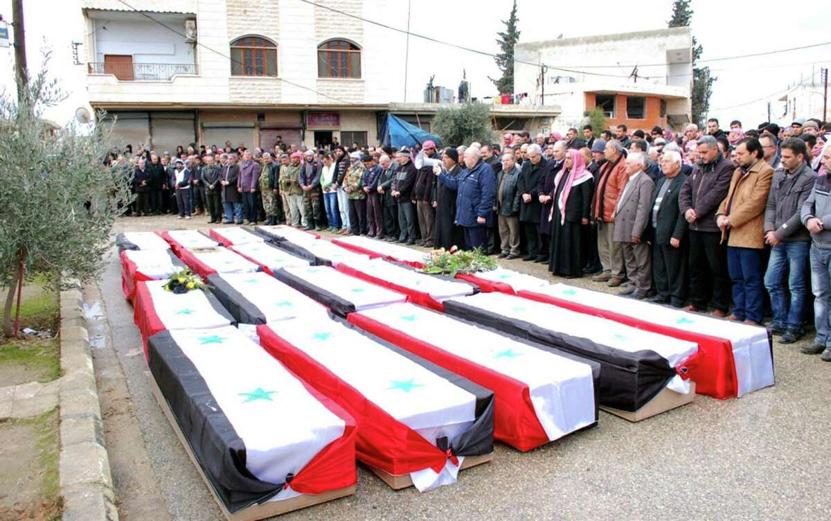 People pay their respects in a photo released by the official Syrian Arab News Agency during a funeral for victims of a massive car bomb in the village of Kafat, in the central province of Hama.