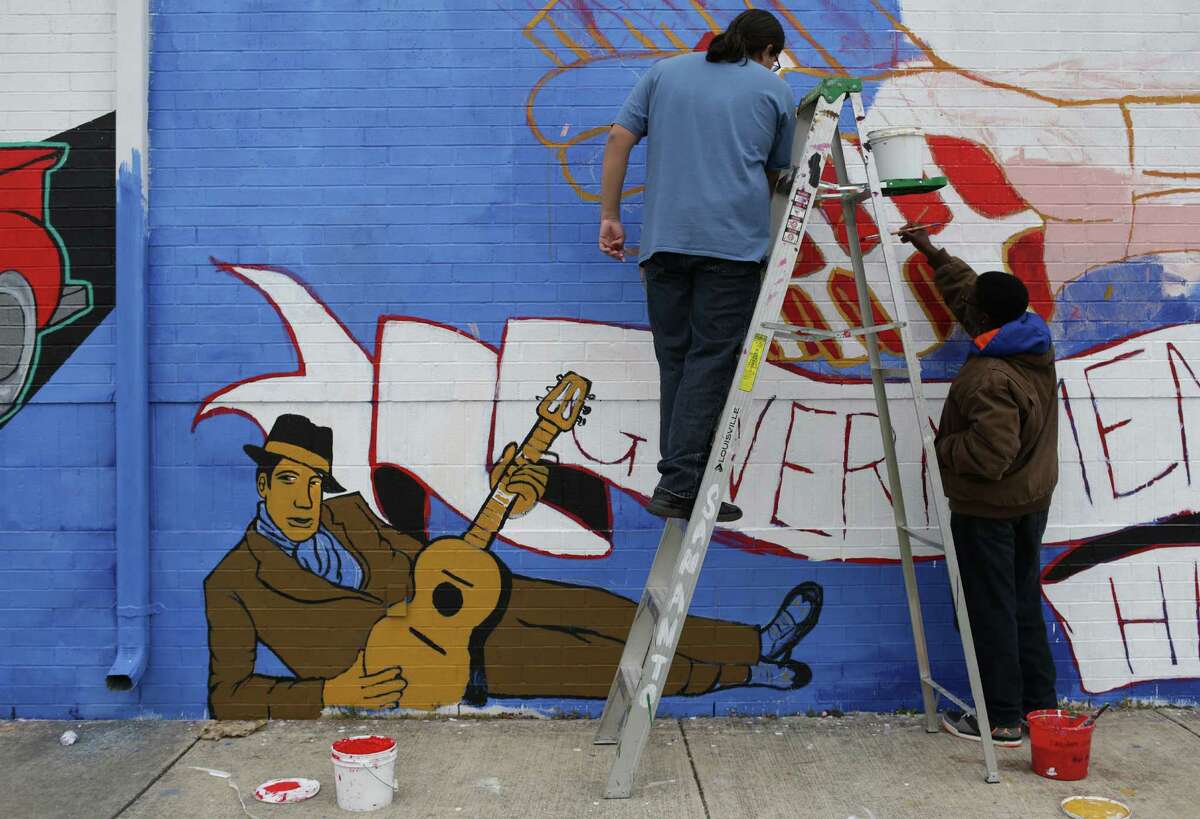 Nikolaos Renfro, right, and Eduardo Zamora add detail to a mural at Center City Health Careers. San Anto Cultural Arts has partnered with Center City Health Careers offering a mural class as an elective at the charter school. Tenth grade students painting a mural on the side of the school. Friday, Dec. 13, 2013.