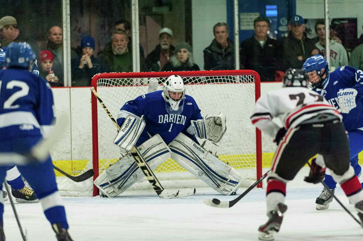 Darien high school goalie Michael Colon keeps his eyes on the puck as teammate Carter Joyce tries to clear it out from in front of the goal during a boys ice hockey game against New Canaan high school played at Darien Ice Rink, Darien CT on Saturday, January, 11th, 2014.