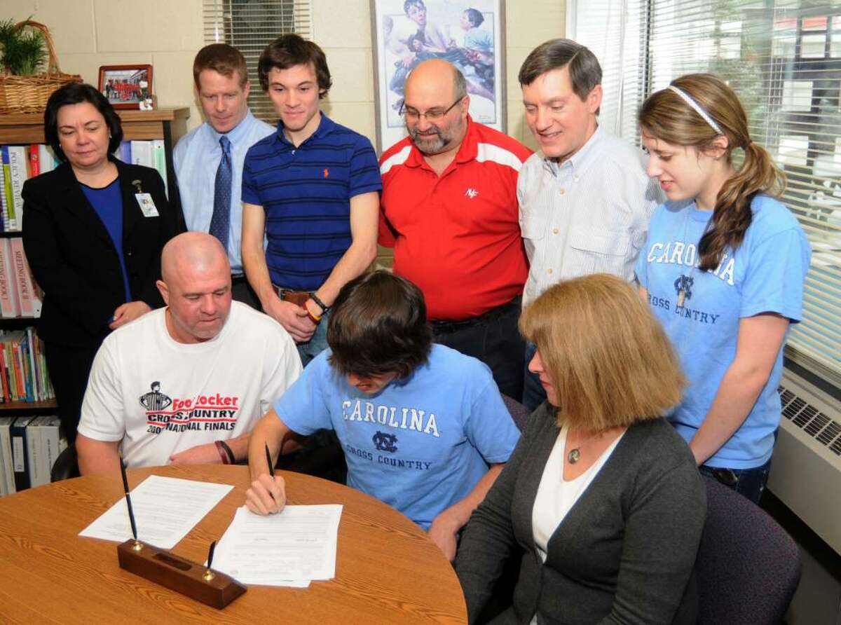John Raneri, center, of New Fairfield, CT, signs a letter of intent to run Track & Cross Country, at the University of North Carolina, next fall, at New Fairfield High School, on Wednesday, Feb. 3, 2010. New Fairfield High school track coach, Tim Murphy, bottom row left, and Raneri's mother, Clare Raneri, bottom row right, witness the signing. Also present at the signing, in back row, left to right, New Fairfield High School Principal, Mariana Coelho, Assistant Principal, Mike Shapleua, Assistant track coach, Jeoff Nelson, Atletic Director, Jay Greenberg, Raneri's father, Jim Raneri and sister, Emily Raneri.