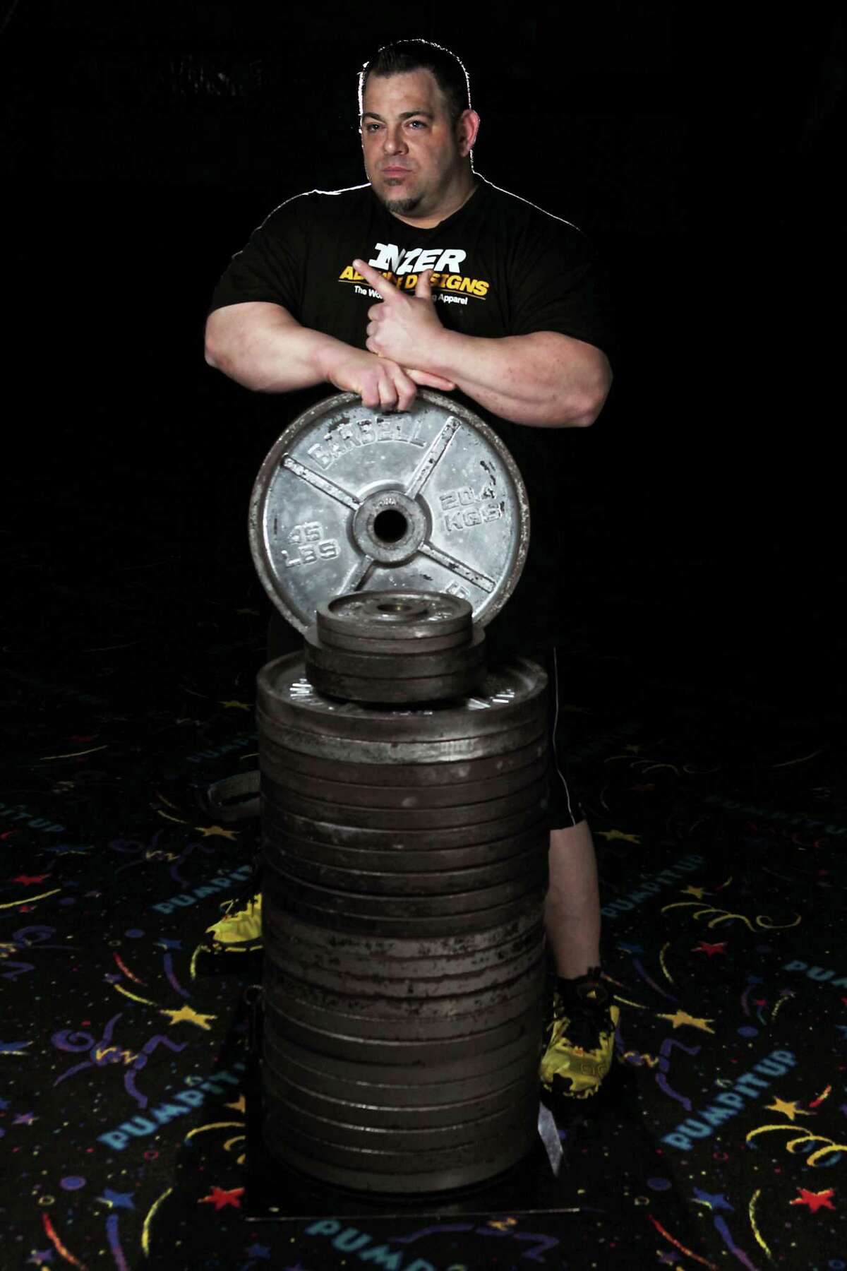 Monster Gym's Tiny Meeker who recently became the first man in the world to bench press over 1,100 pounds poses for a portrait with 1,100 pounds of weights Sunday, Jan. 12, 2014, in Kingwood.