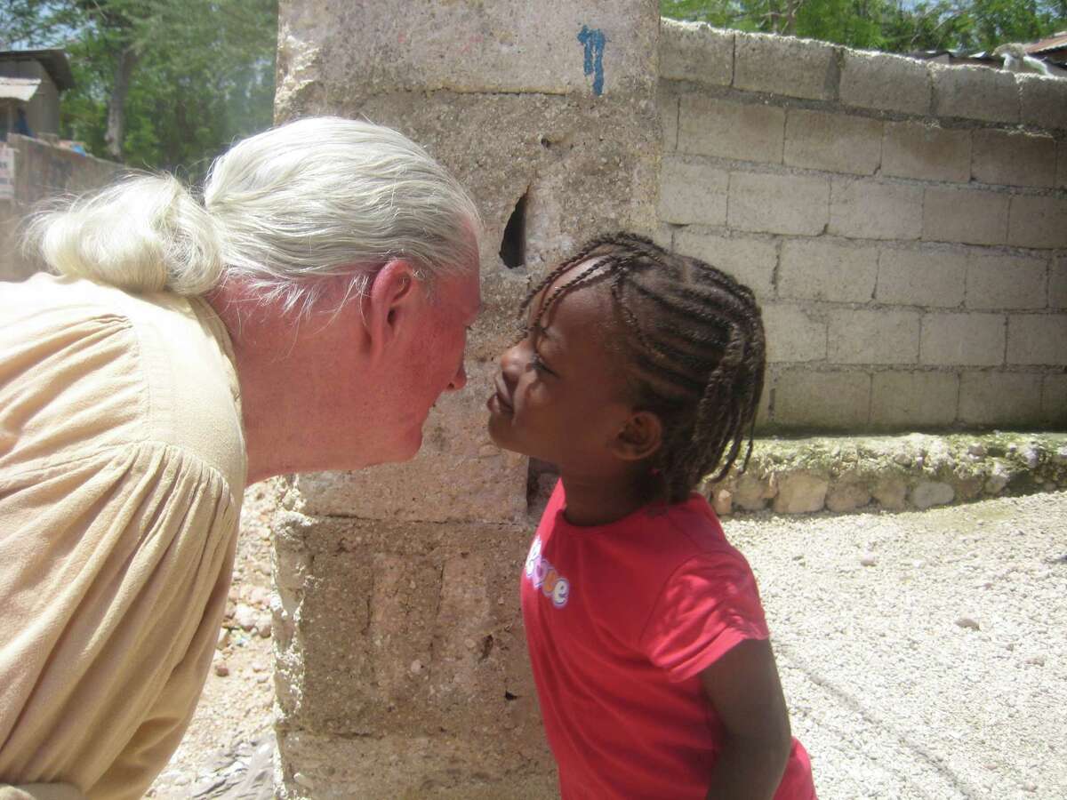 Gerard Brooker receives a kiss on the cheek from a tiny tot in Haiti. Brooker has traveled to more than 100 countries to raise awareness about the plight of children who are hungry, or who have suffered because of wars or other tragic circumstances. When called upon, he uses the art of clowning to bring some joy to these children.