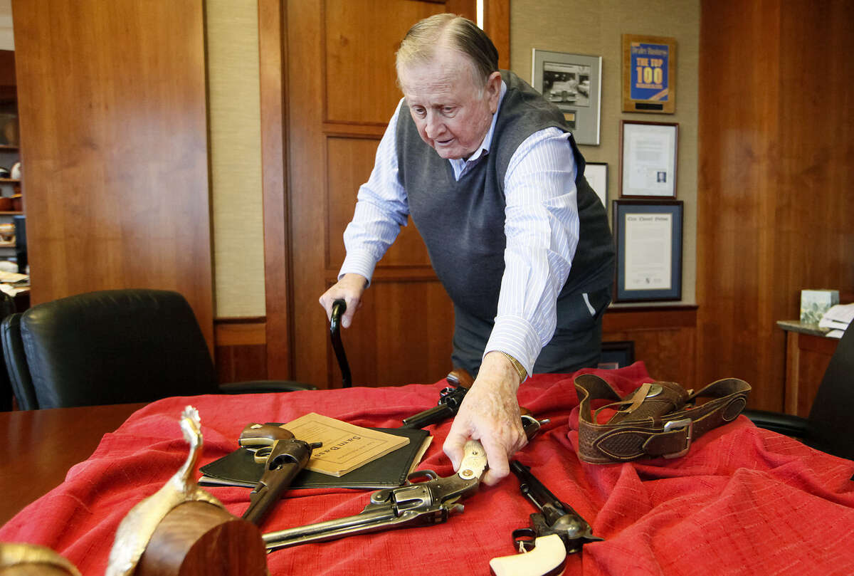 B.J. "Red" McCombs reaches for a 1933 pistol during an interview in his San Antonio office. It's part of his extensive collection.