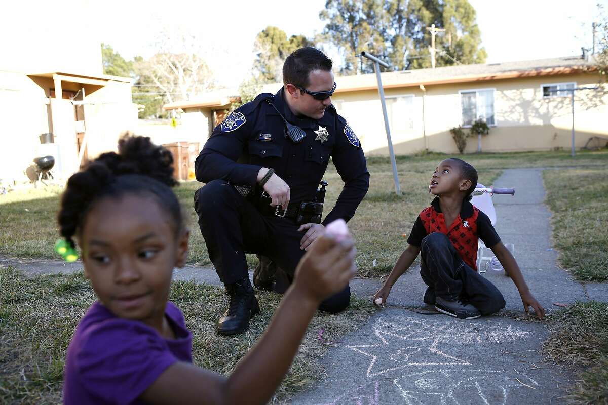 While on foot patrol, Officer Carducci talks with Jayon Evans, 4, while he and his sister Jayonia Evans, 5, draw with chalk on the sidewalk in the San Pablo Housing Projects in San Pablo, CA, Tuesday, January 14, 2014. San Pablo, CA, with a population of 30,000, had zero homicides last year, due in part to the police taking a more active role in the community with increased foot patrols, interactions with citizens and youth programs.