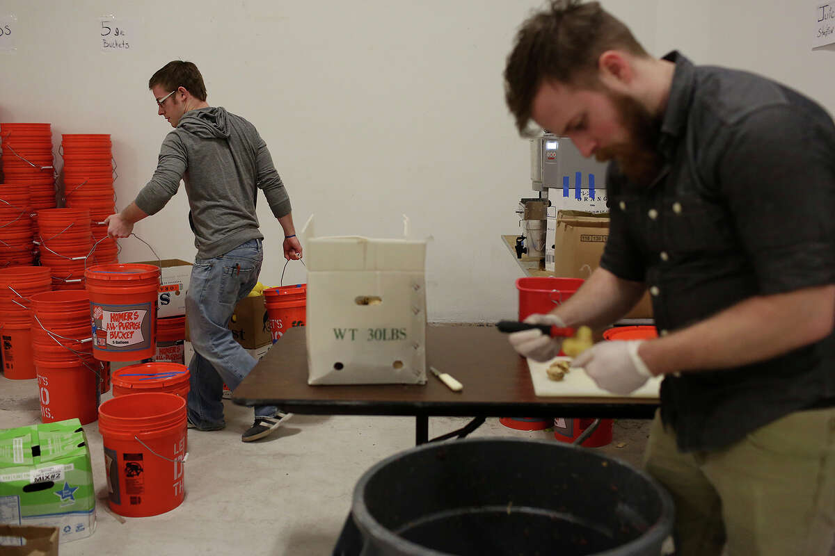 Samuel Gauthier, of Madison, WI, right, peels ginger while Alex Smith, a bartender at Bohanan's, left, moves buckets in preparation for this weekend's San Antonio Cocktail Conference on Tuesday, Jan. 14, 2014.