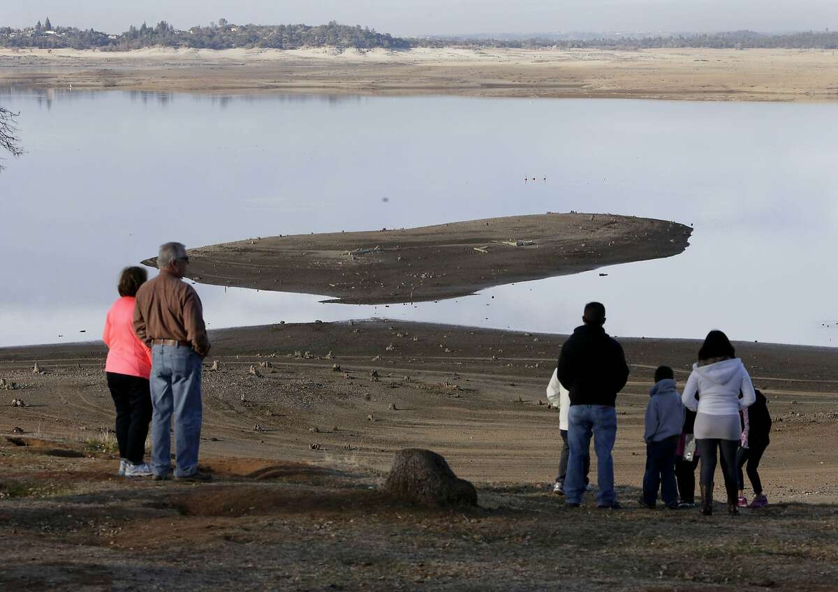 Visitors to Folsom Lake, can view some of the remains of structures of the old gold rush town of Mormon Island, in background, near Folsom, Calif., Thursday, Jan. 9, 2014. Gov. Jerry Brown said he would meet Thursday with his recently formed drought task force to determine if an emergency declaration is necessary as California faces a serious water shortage. Reservoirs in the state have dipped to historic lows after one of the driest calendar years on record
